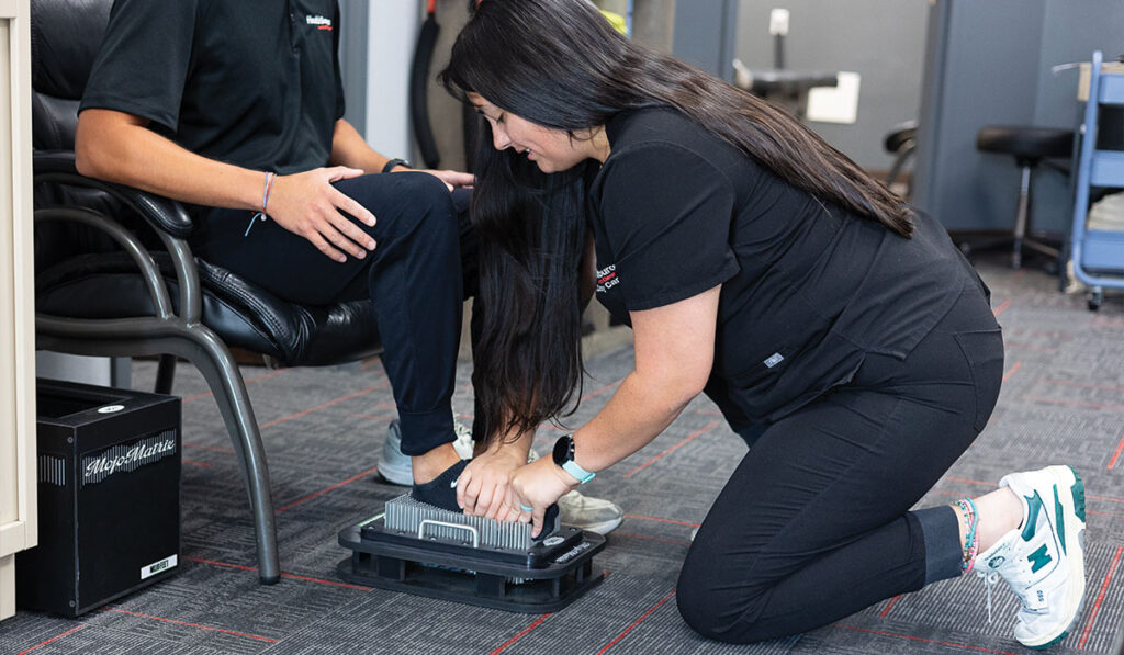 A patient being measured for orthotics using a 3D foot scan at HealthSource of Nine Mile.
