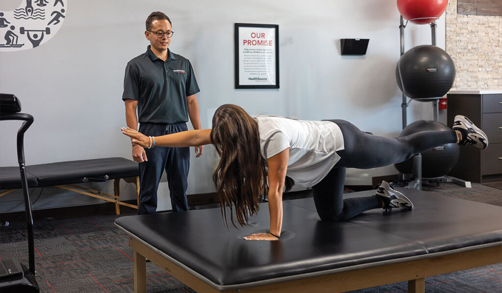 A patient doing stretches with a Rehabilitation Specialist at HealthSource of Nine Mile.