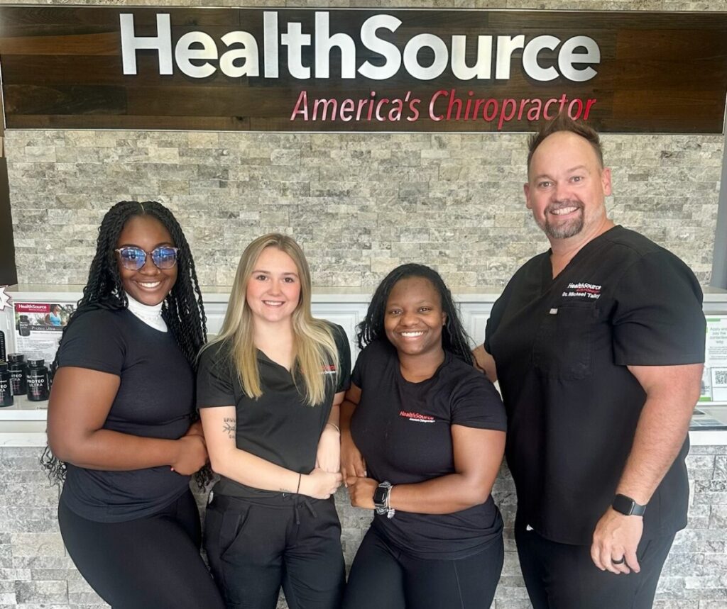 Dr. Talley and team posing together at the front desk at HealthSource of Spanish Fort.