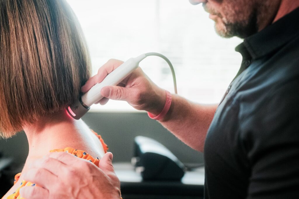 Close up of practitioner applying laser treatment to patient's neck.