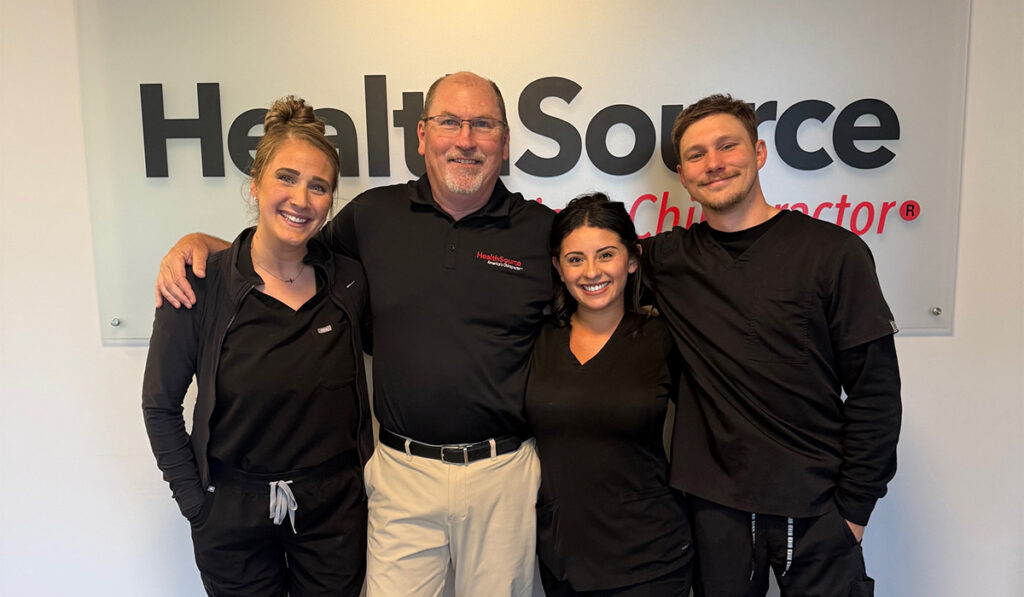 Dr. Todd McGilvra and the team at HealthSource of Brentwood posing together in front of the HealthSource sign.