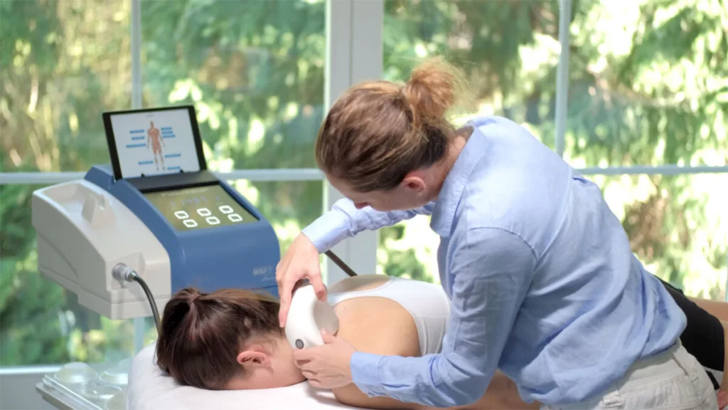 Shockwave therapy treatment applied to patient’s shoulder in chiropractic clinic for pain relief and recovery