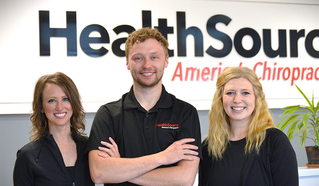 Dr. Kristin Kruger, Dr. Andrew Doyle and Dr. Hannah Anderson standing together at the front desk at HealthSource of Buffalo.