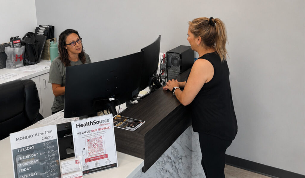 The front desk specialist at HealthSource of Burleson greeting a patient.