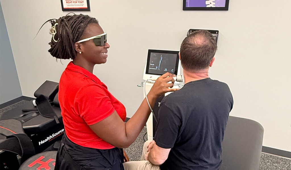A chiropractor performing Class IV Laser Therapy on a patient.