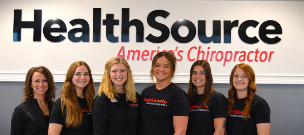 The team at HealthSource of Buffalo standing in front of the clinic sign near the front desk.